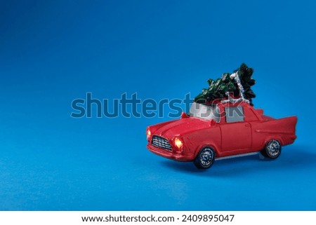 A small red toy with a green Christmas tree on the roof, on a blue background