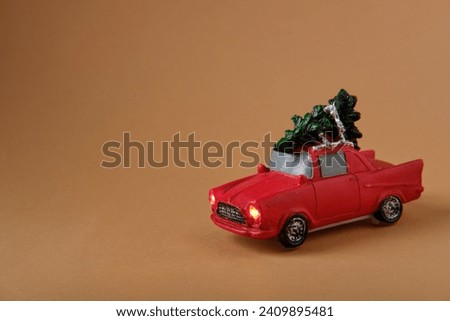 Red car with a Christmas tree on an orange background, Christmas