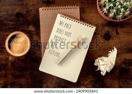 Inspirational and motivational saying, My Past Does Not Predict My Future, written in a notebook, overhead flat lay shot on a rustic wooden desk