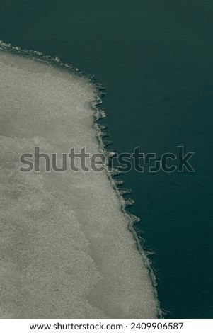 Top down aerial winter view of frozen Green lakes ice texture with cracks near shore with lake bridge in Kharkiv Ukraine
