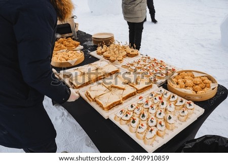 Catering outside in winter, serving food in the cold, guy putting sandwiches on trays. High quality photo