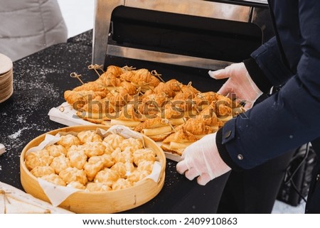 Hands lay out food on the table, cheese sandwiches, off-site catering on the street, treats, sweet buns. High quality photo