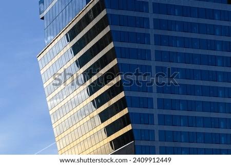 Slanted surface of a modern glass skyscraper exterior at sunset Royalty-Free Stock Photo #2409912449