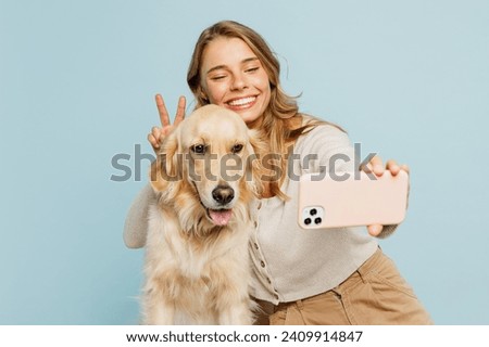 Young owner woman with her best friend retriever dog wears casual clothes do selfie shot on mobile cell phone show v-sign isolated on plain pastel light blue background. Take care about pet concept