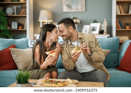 Couple eating pizza at home. They are enjoying in weekend. Valentine's day at home.