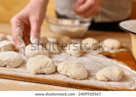 A woman forms pieces of dough for making donuts. The process of making donuts Royalty-Free Stock Photo #2409920567