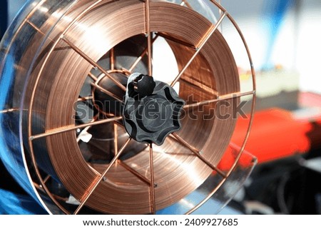 Copper covered welding wire coil on arc machine closeup. MIG MAG welding equipment Royalty-Free Stock Photo #2409927685