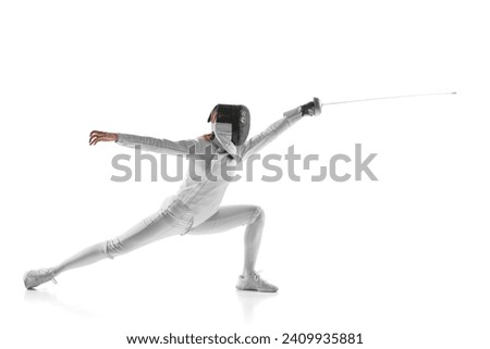 Artistry and combat. Electrifying photo of finesse of female fencer in motion, sword gleaming, against white studio background. Concept of professional sport, active lifestyle, fitness, strength. Royalty-Free Stock Photo #2409935881