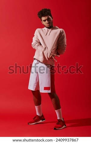 cool african american man in gym clothes showing v gesture and pouting lips on red background