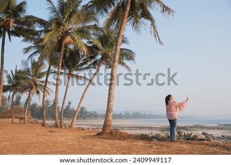 A middle age women taking selfie at the beach in the evening. Kondivali, Raigad, Maharashtra, India, Asia.