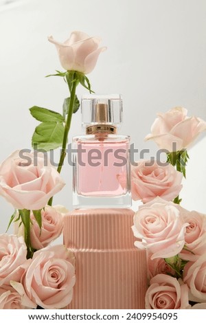 Close-up of an unlabeled perfume bottle displayed on a podium with fresh roses decorated around it. Roses are commonly used in the perfume industry. Royalty-Free Stock Photo #2409954095