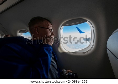 a passenger sits by the window on an airplane with a surprised and frightened look