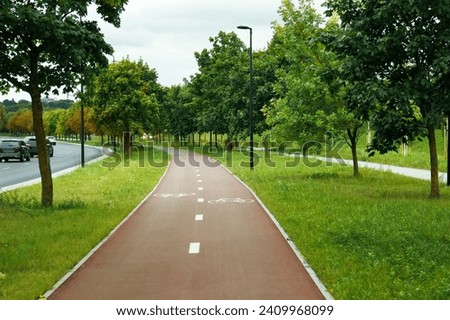 View of city park with bicycle lane and trees Royalty-Free Stock Photo #2409968099