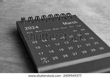 Black and white March 2024 desk calendar on wooden desk. New month concept