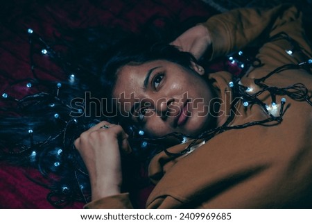 cool multiracial girl with a decorative light, playing with a decorative lights in her bed, photography with light.
