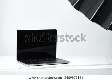 Laptop with black screen and photography equipment in photostudio