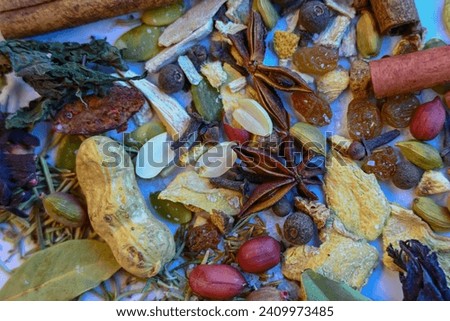 close-up of a vegetable mixture consisting of nuts, raisins, cinnamon sticks, cloves, ginger, pepper, pumpkin seeds, bay leaves and various dried herbs.