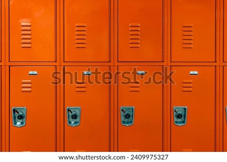 Orange metal lockers along a nondescript hallway in a typical US High School.  No identifiable information included and nobody in the hall.	 Royalty-Free Stock Photo #2409975327