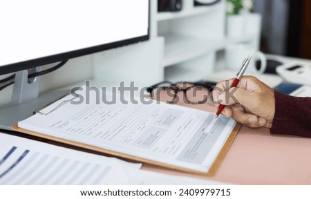 A man working on desk at home reading document before filling out various information and sign in the document, Concept of working online at home, close-up shot