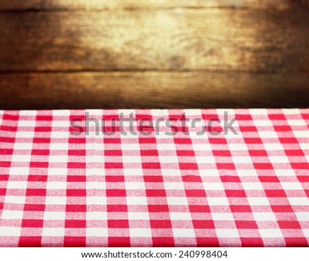 Checkered red tablecloth over rustic wooden background