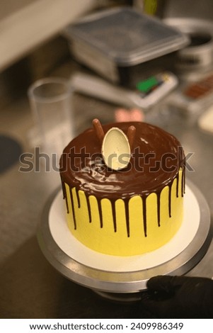 pastry chef smooth prepare sculpt yellow dripping frosted layered dark chocolate cake ornate high res image