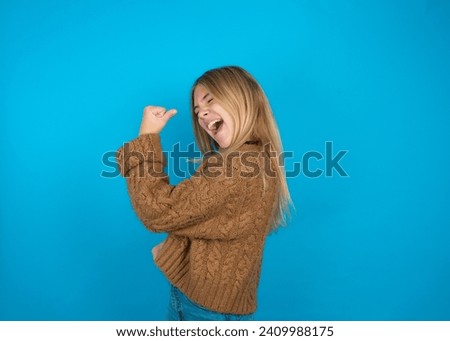 Portrait of funny Caucasian teenager girl  shout yeah raise fists hands celebrate victory game competition