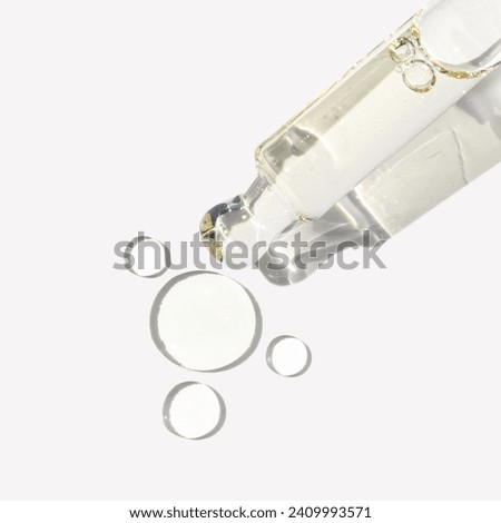 Clear serum in glass dropper with texture drops on white background