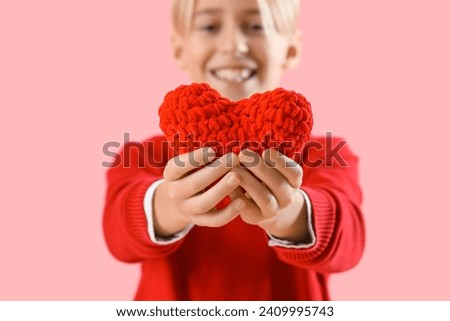 Cute little boy with red heart for Valentine's day on pink background