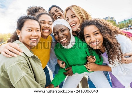 Multi ethnic group of young women hugging outside - Happy girlsfriends having fun laughing out loud on city street - Female community concept with cheerful girls standing together - Women  power  Royalty-Free Stock Photo #2410006043