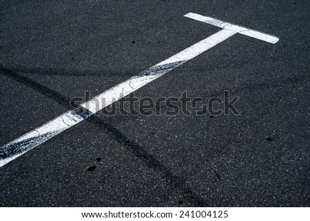 Asphalt surface of the empty parking with white road marking lines and wheel tracks