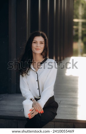 Beautiful Woman Going To Work With Coffee Walking Near Office Building. Portrait Of Successful Business Woman Holding Cup Of Hot Drink. High quality photo