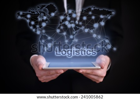 businessman holding a tablet PC with the projection map of the world on the screen. icons and citys around the world. global logistics. jlogistics. International logistics business concept