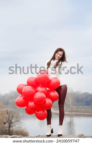Young woman with red balloons, outdoors, full length photo.. Valentine's day concept