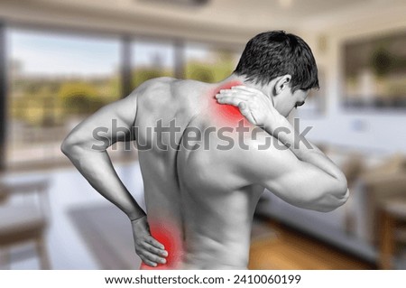 Young sporty trainer in gym with back pain. Workout concept
