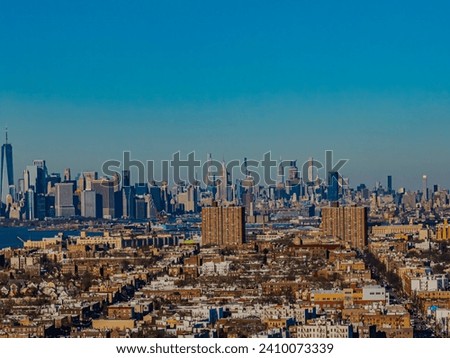 An aerial view of a residential neighborhood in Brooklyn, NY. The NYC skyline is in the background on a sunny day.