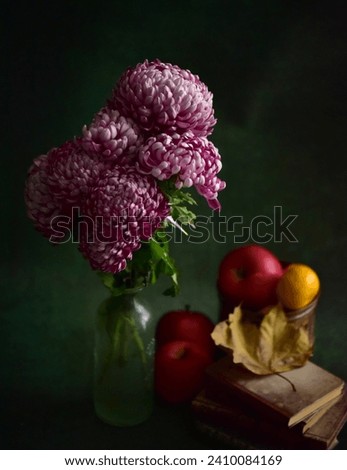 Purple flovers in a vase, books and fruits on a table