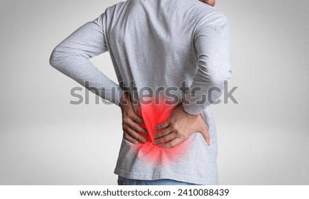 Lower back pain. Man holding his back in pain. Medical concept. Isolated on white studio background. Royalty-Free Stock Photo #2410088439