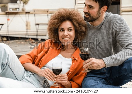Cheerful loving couple husband and wife spending time together on celebration with red wine, traveling together by camper van motor wheel home trailer, having romantic picnic