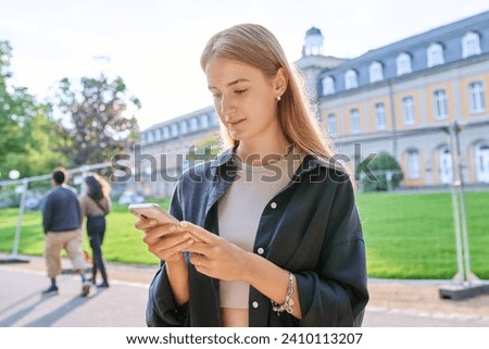 Young teenage female student using smartphone, outdoor