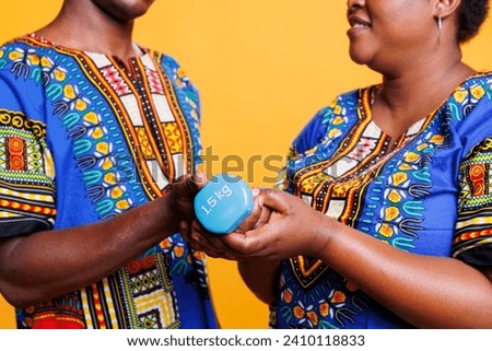 Black man and woman couple holding dumbbell in hands while exercising together closeup. Boyfriend and girlfriend lifting gym equipment, training muscles and doing workout