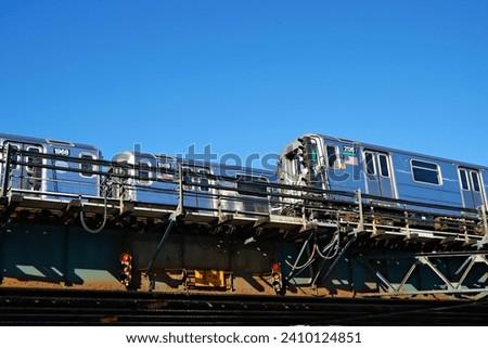Two shiny bright metal silver elevated subway trains crossing under a clear blue sunny sky. Royalty-Free Stock Photo #2410124851