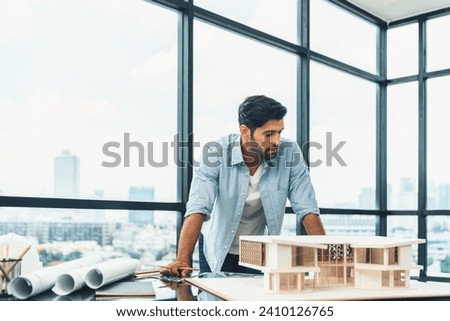 Smart civil architect engineer looking while planing design house construction with blueprint, house model and architectural equipment. Designer measuring and inspecting house model. Design. Tracery. Royalty-Free Stock Photo #2410126765