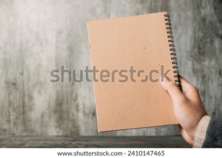 A business hand holding a notebook on a blurred background. Empty notebook for copy space