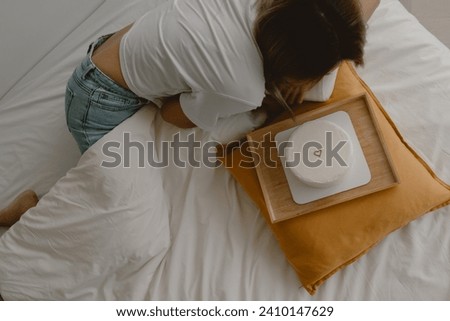 Above view of Asian woman wears jean and white t-shirt looking at birthday cake on the bed.