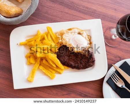 Picture of delicious fried pork with fried eggs and french fries at plate