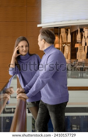 Man and woman dressed in the same purple sweaters, looking at each other with love. Valentine's Day. Romantic date. Knee-deep photo.