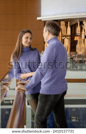 Man and woman dressed in the same purple sweaters, looking at each other with love. Valentine's Day. Romantic date. Knee-deep photo.