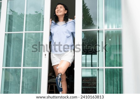 Women with disability with prosthetic legs opened the door and looked away, Cheerful woman standing by the patio door at home	