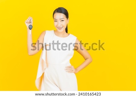 Portrait beautiful young asian woman smile with car key on yellow color background