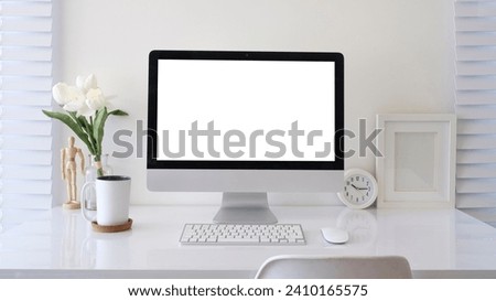 Modern workplace with computer pc, books, alarm clock and coffee cup on white table.